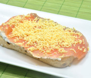 Un base de pan tostado con salsa remoulade y salmón ahumado. Y por encima un toque de yema rallada